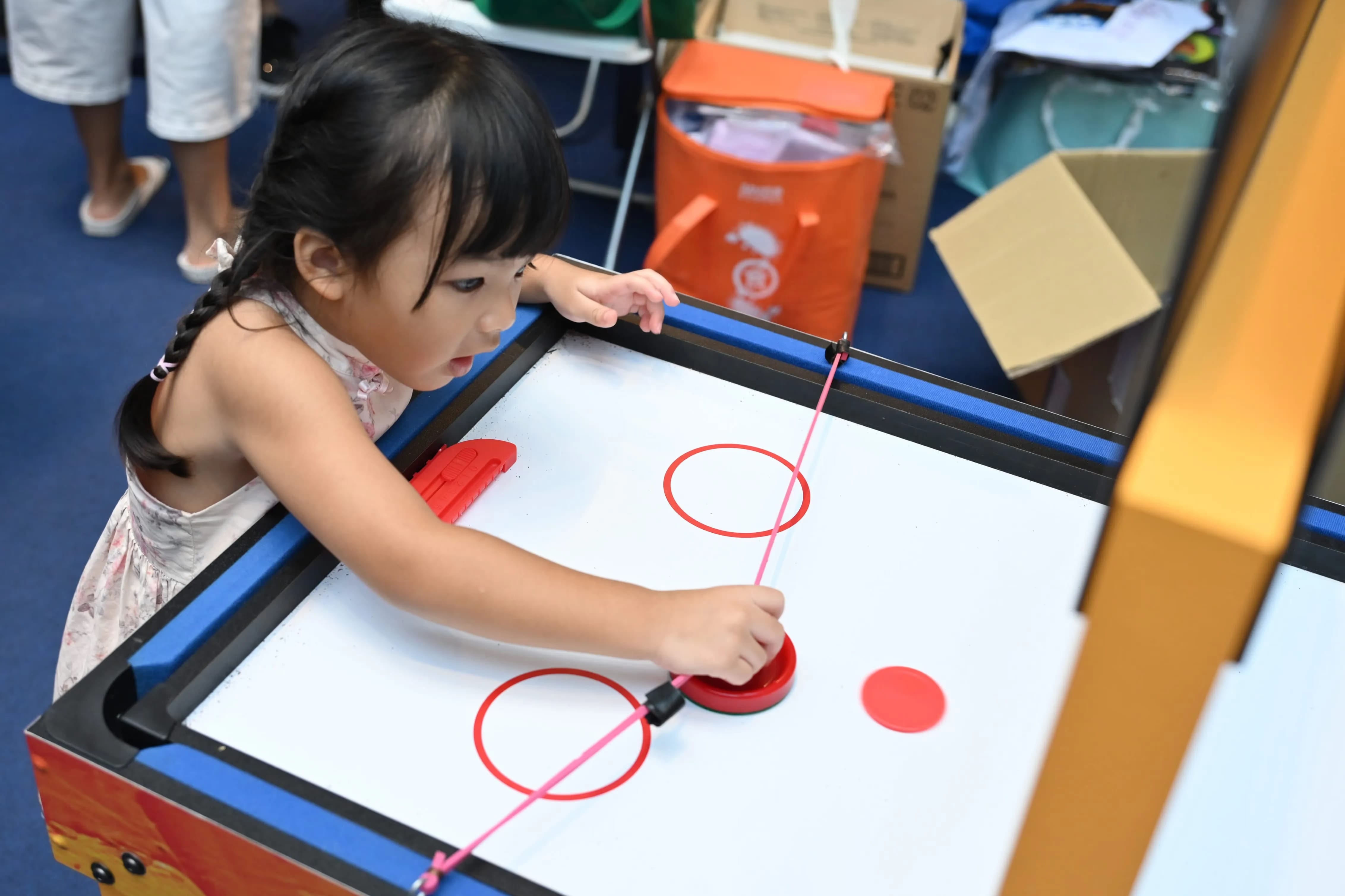 Girl playing table hockey with resistance bands .